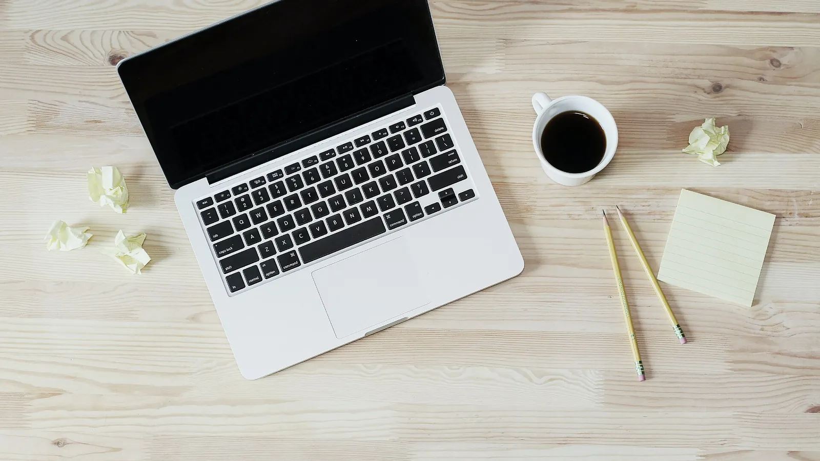 Laptop, coffee and notepaper on a light wooden desk
